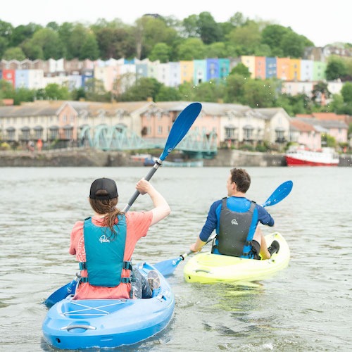 Couple kayaking in Bristol Floating Harbour with iconic coloured houses of Hotwells in background