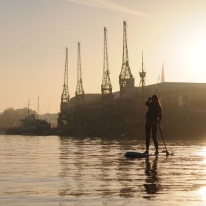 sun rises over Bristol Harbour solo paddleboarder