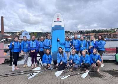 Hen group posing with paddleboards before their hen do in Bristol paddleboarding session